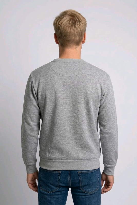 Person wearing a gray sweater and blue jeans against a white background