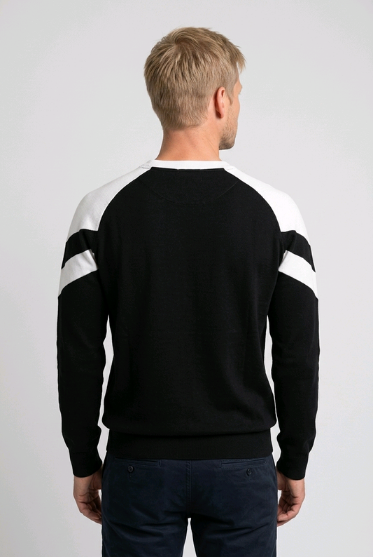 Man wearing a black sweater with white sleeves on a plain background