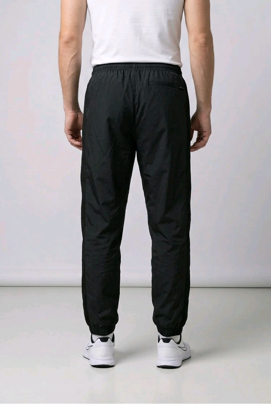Man wearing black Nike tracksuit bottoms back view