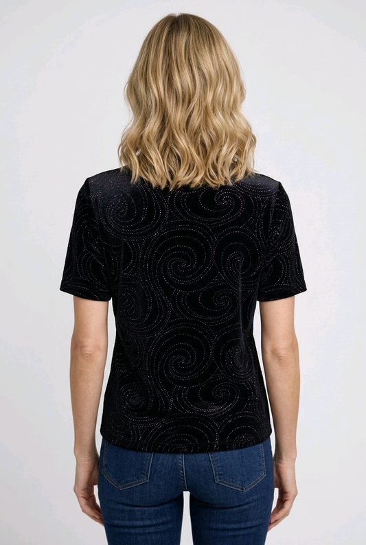 Woman wearing a black patterned top with blue jeans