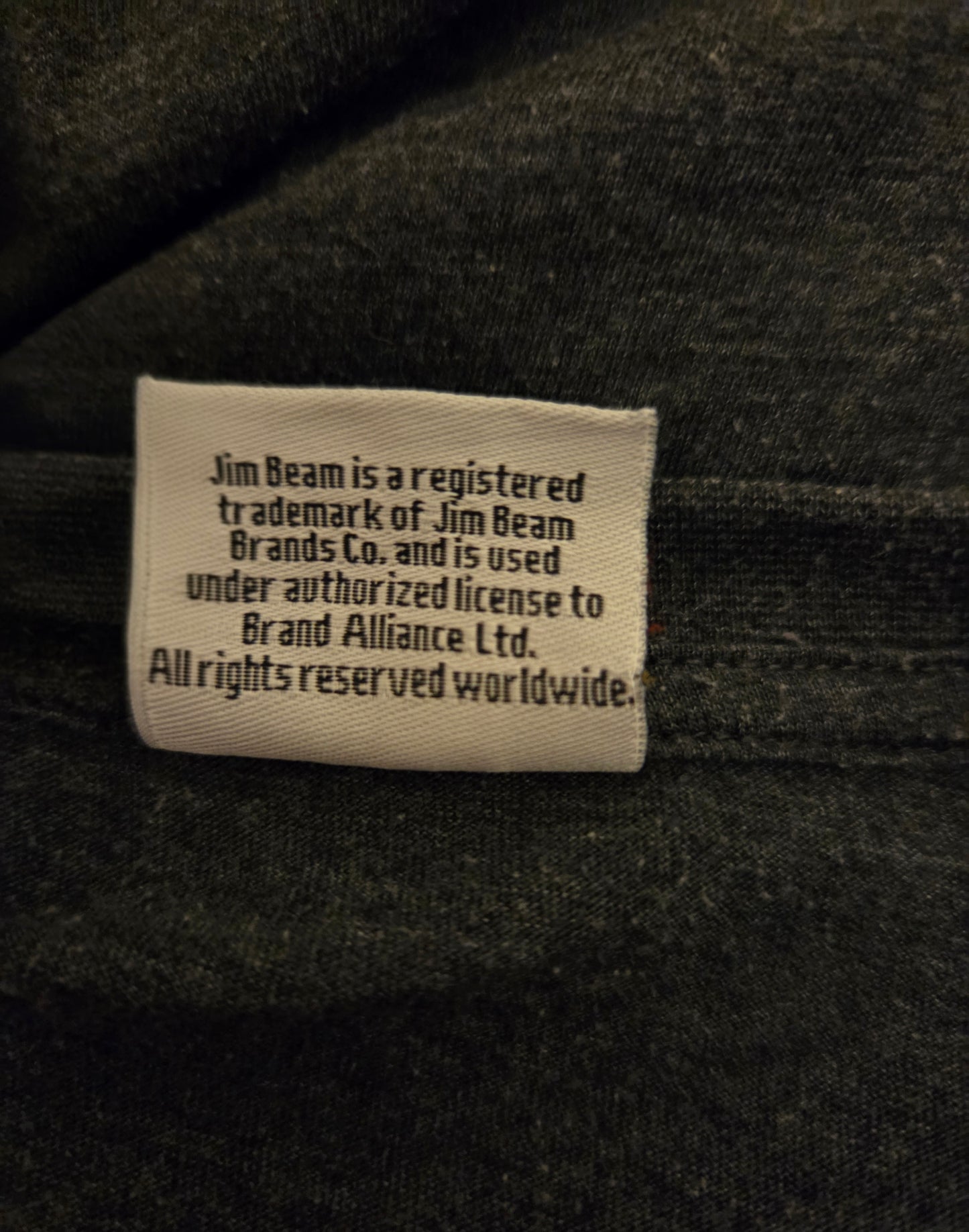 Label on a dark fabric background with text about Jim Beam branding.