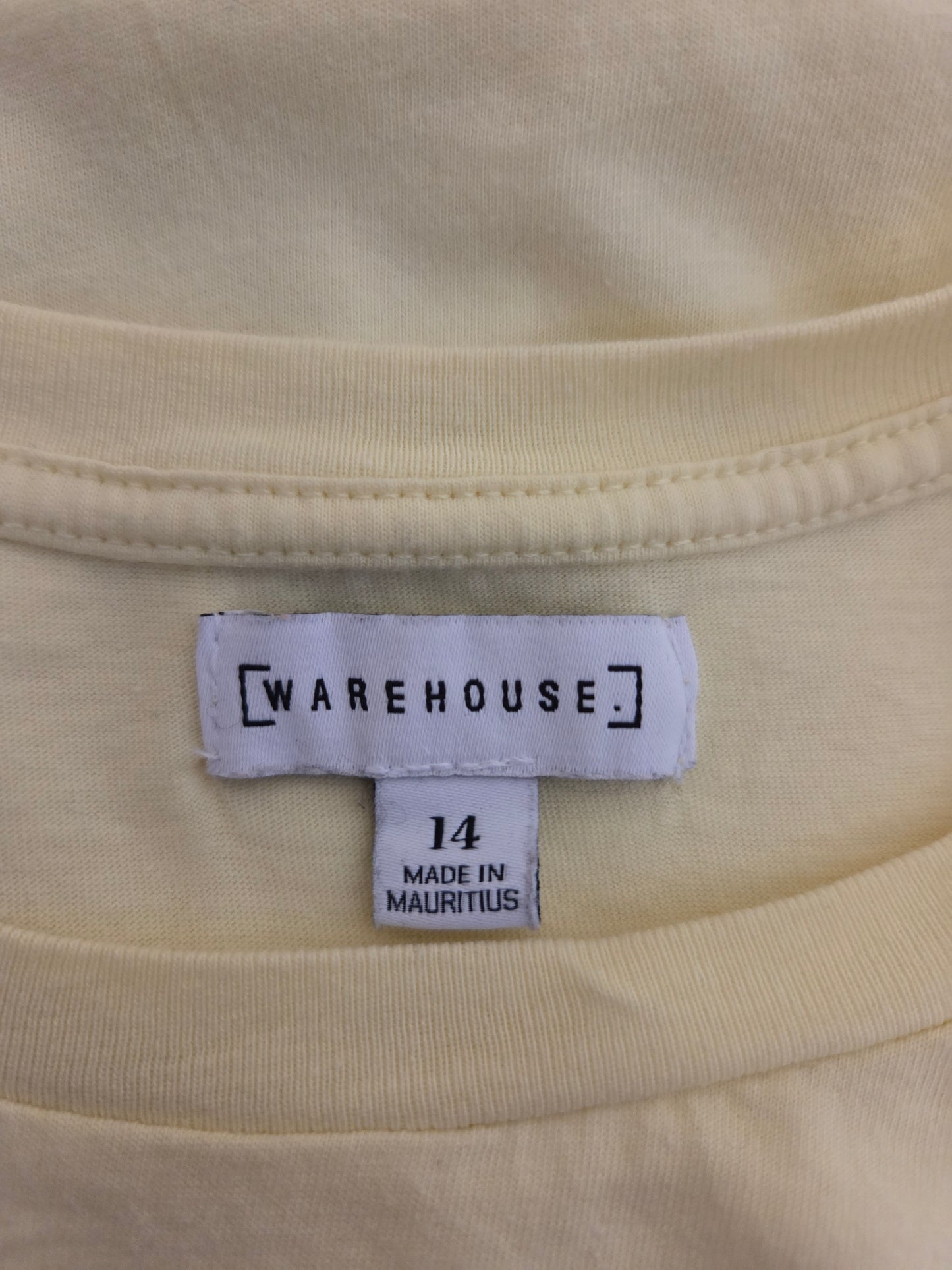 Close-up of a yellow fabric with a 'Warehouse' size label