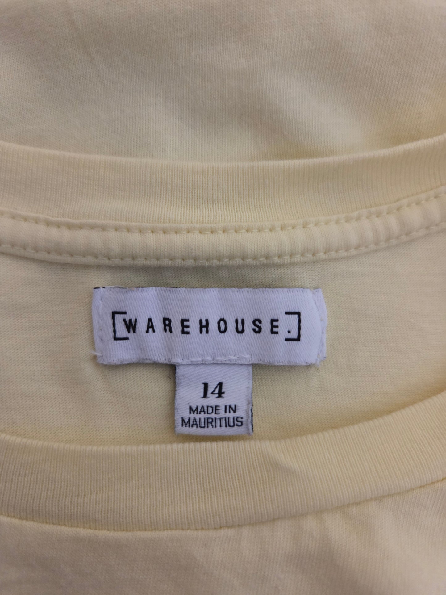 Close-up of a yellow fabric with a 'Warehouse' size label