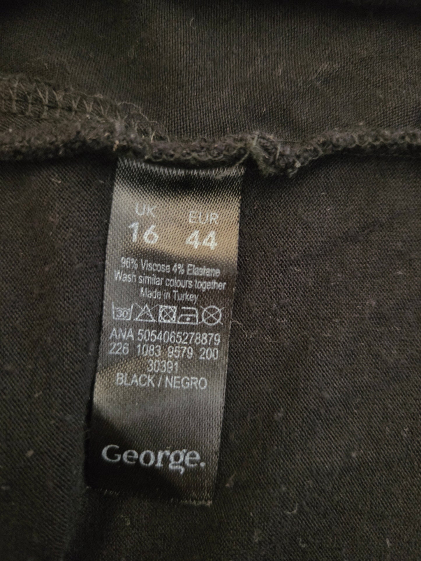 Clothing label on a dark fabric with brand name 'George'.