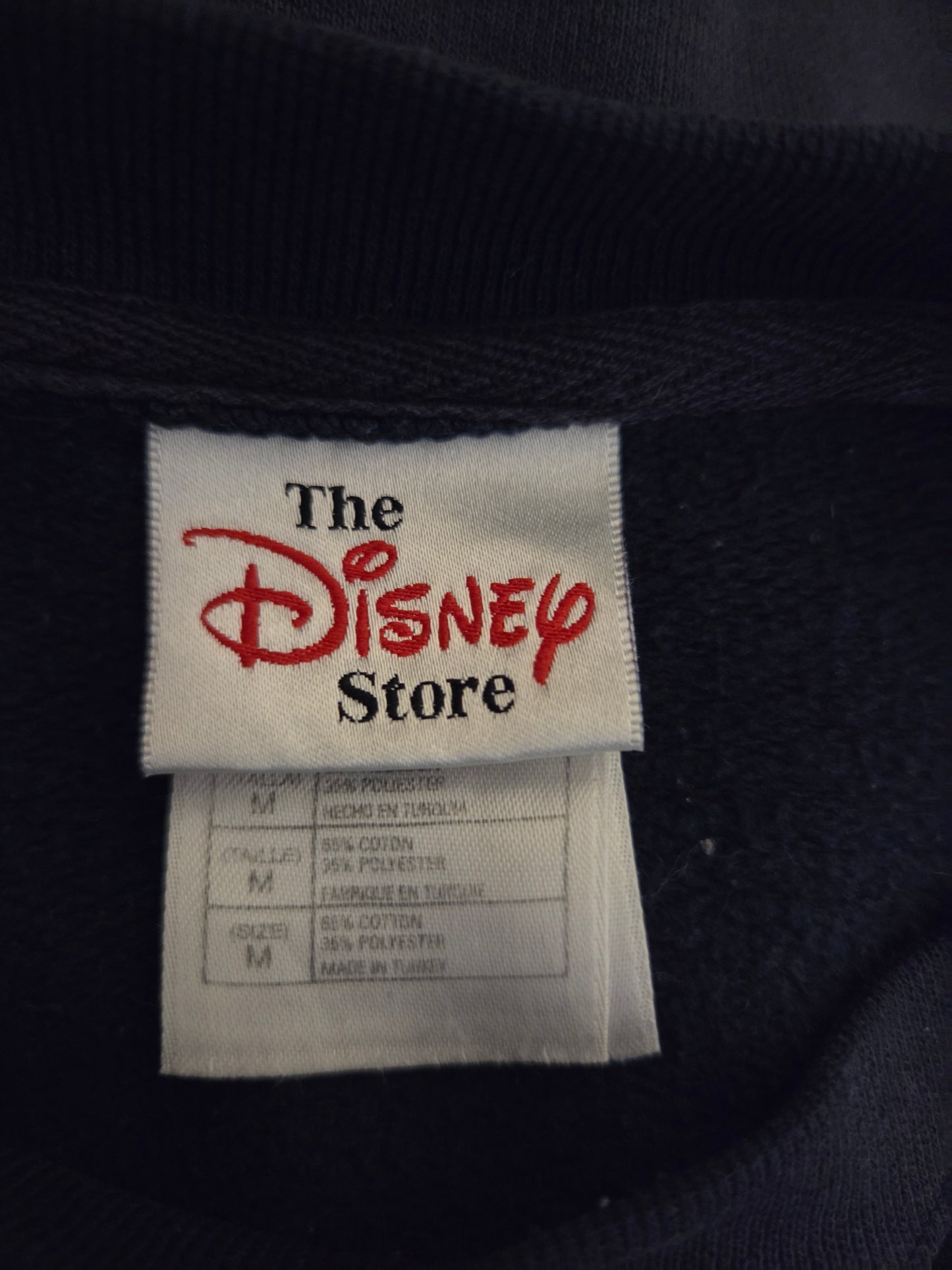 Label from The Disney Store on a dark fabric background