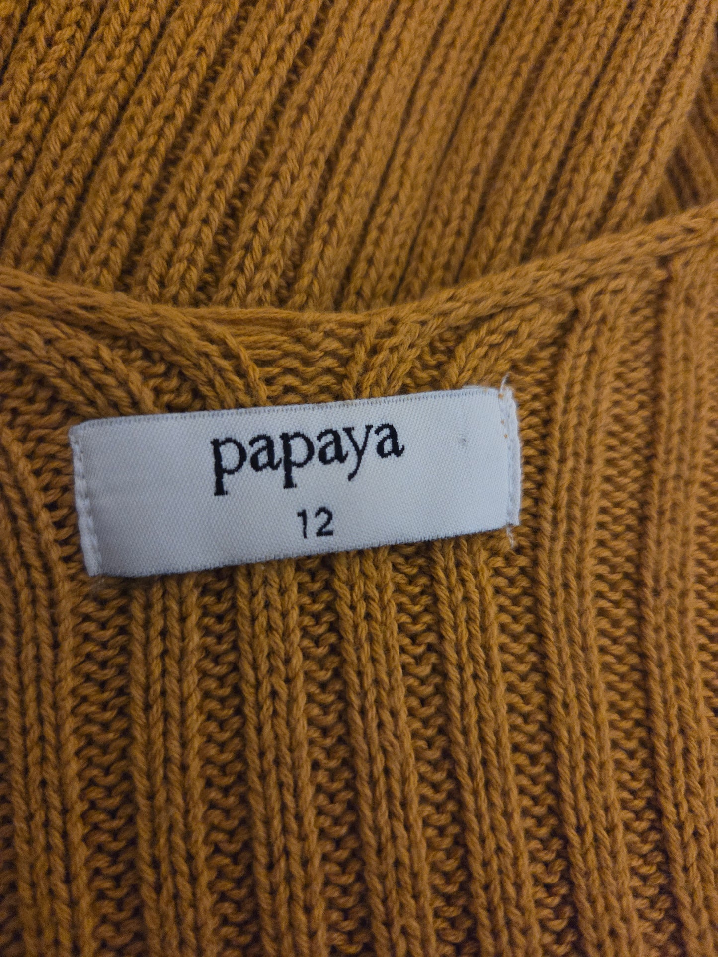 Close-up of a mustard yellow fabric with a 'papaya' label on a textured background