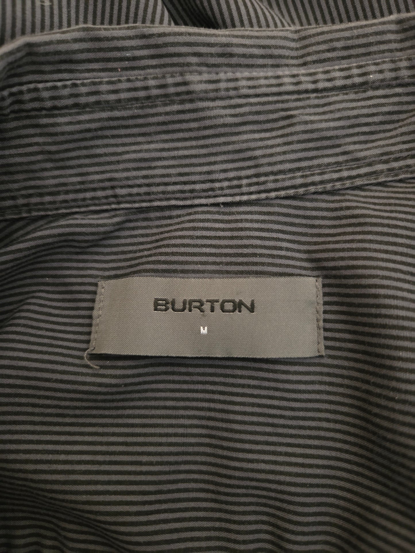 Close-up of a striped shirt with a Burton label on a dark background