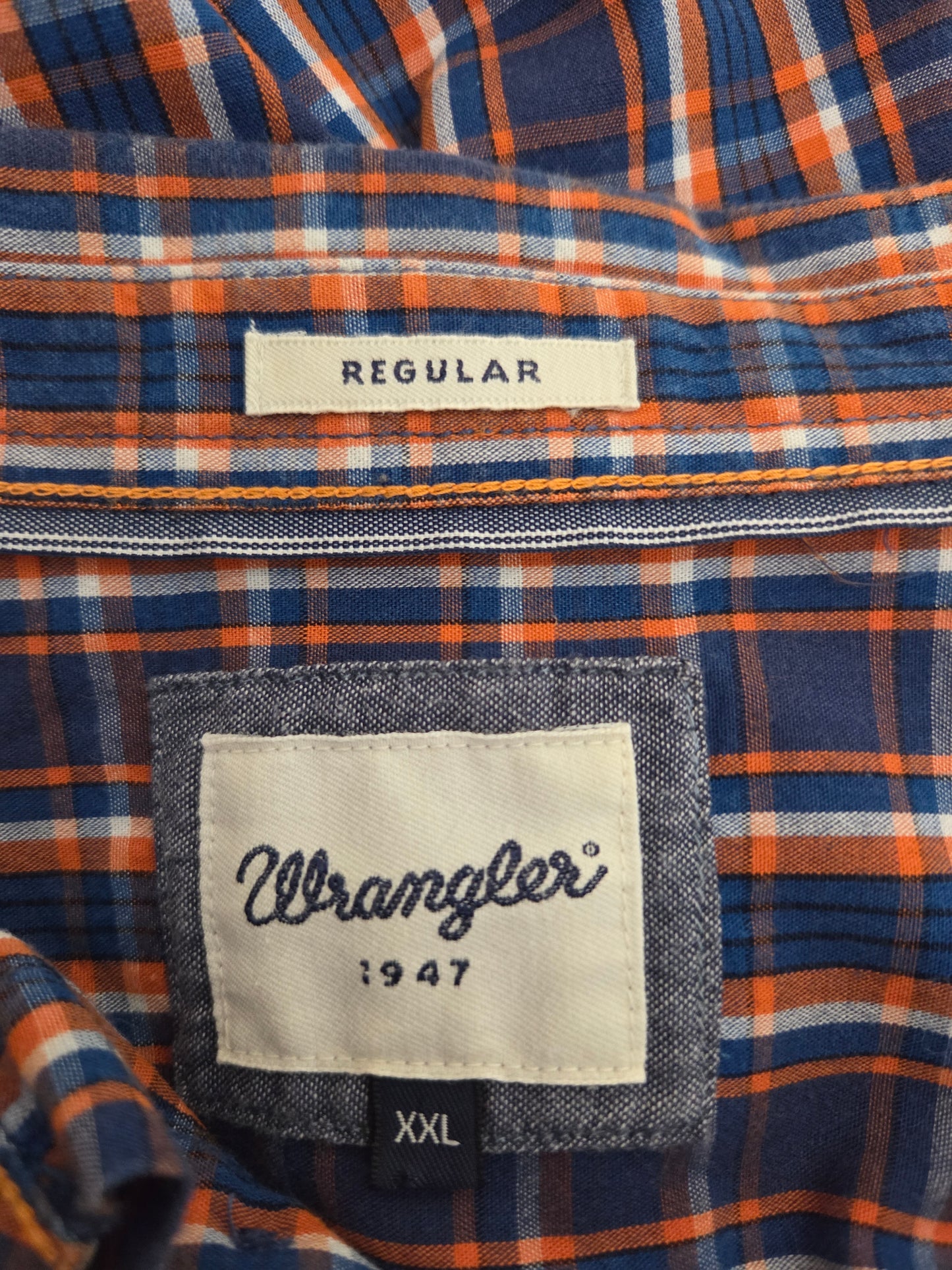 Close-up of men's plaid shirt fabric in blue, orange, and white check pattern