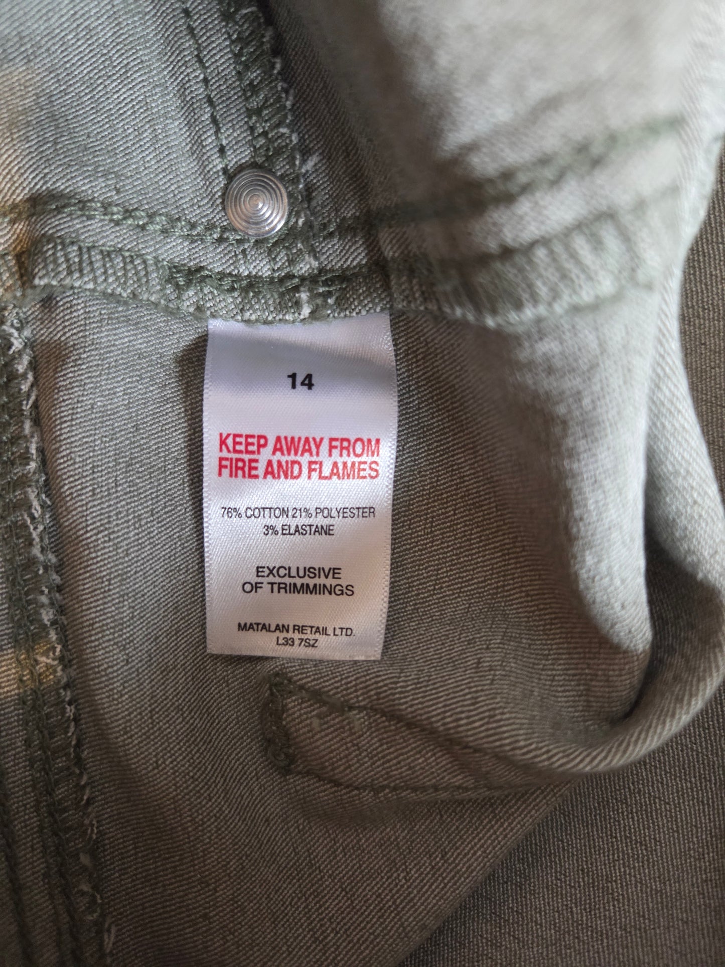 Close-up of a size label on olive green shorts