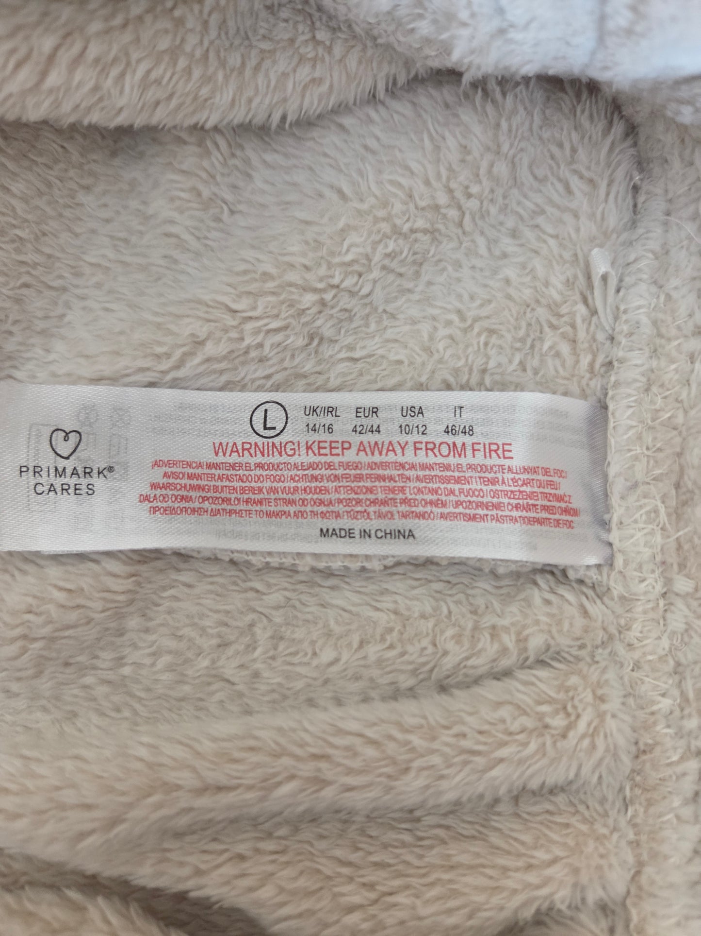 Close-up of a size label on a textured fabric surface with 'Primark' branding.
