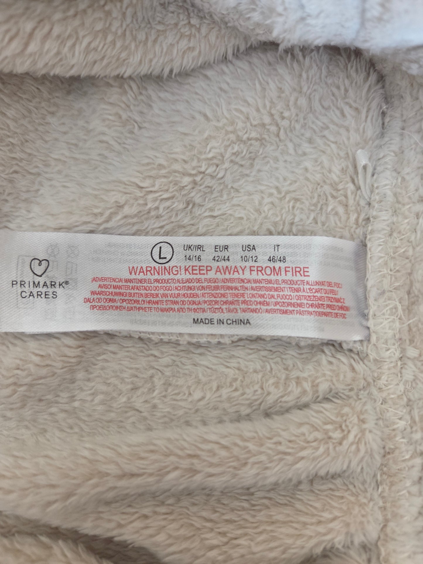 Close-up of a size label on a textured fabric surface with 'Primark' branding.