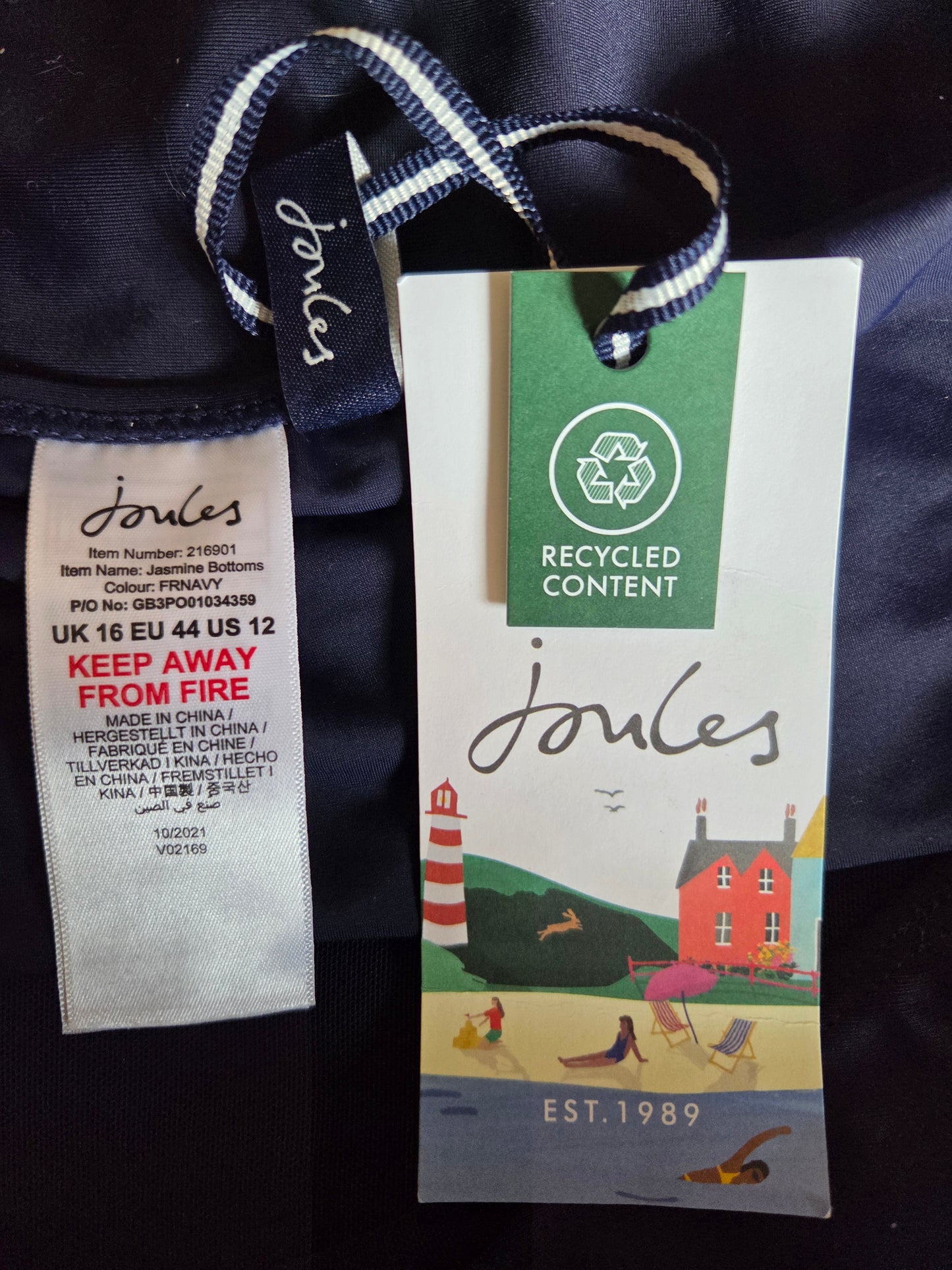 Close-up of Joules clothing tags with recycled content label on a dark fabric background