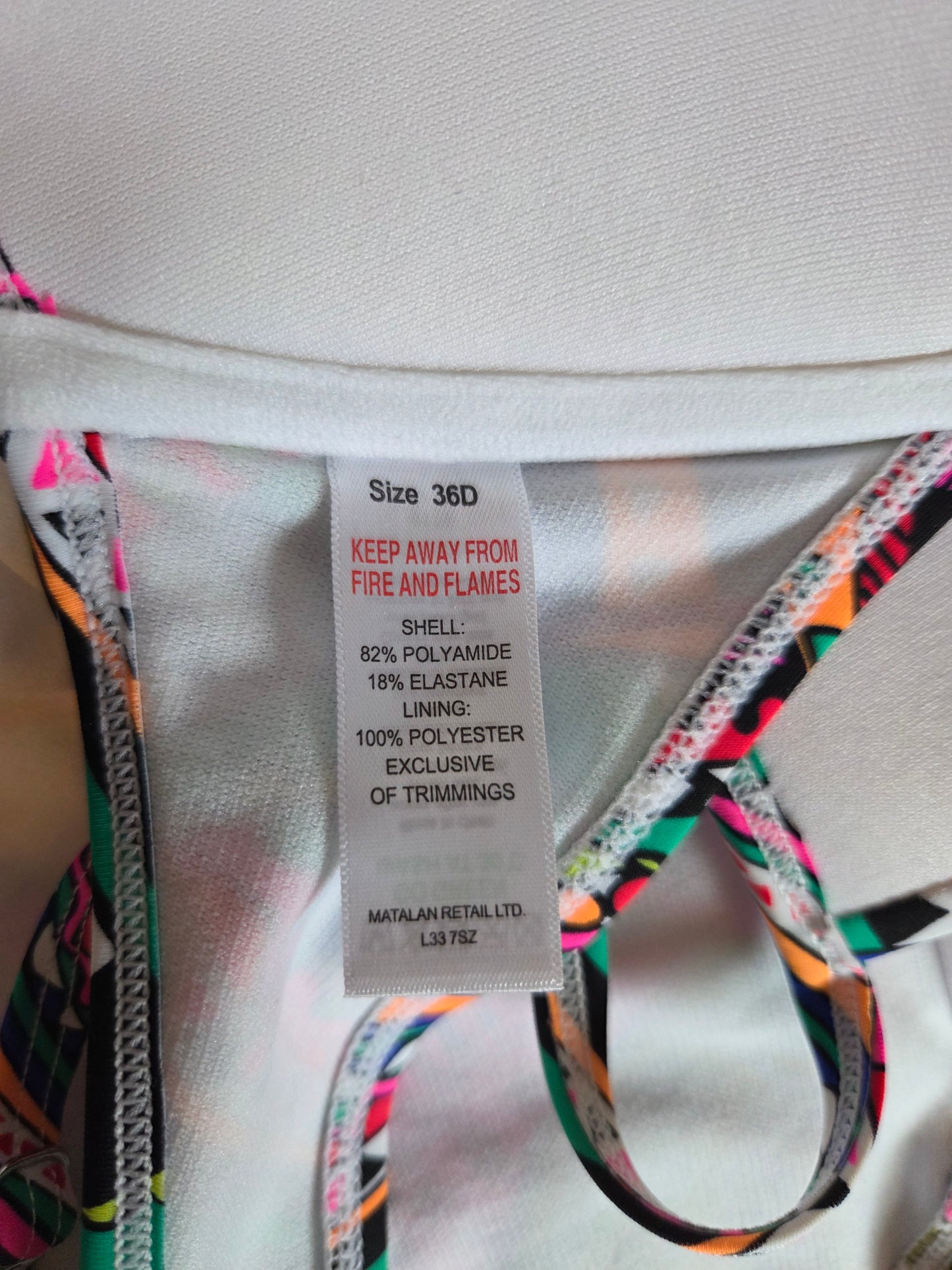 Close-up of a clothing label on a garment with multicolor trim.