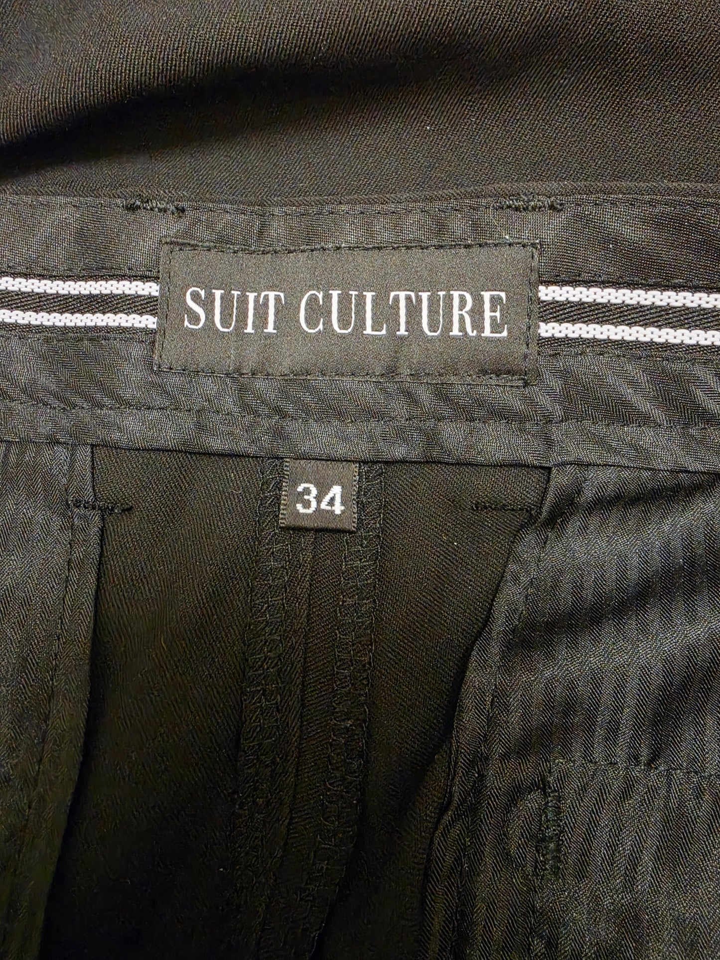 Close-up of the inner waistband showing a fabric label that reads 'SUIT CULTURE' and a size tag marked '34'.