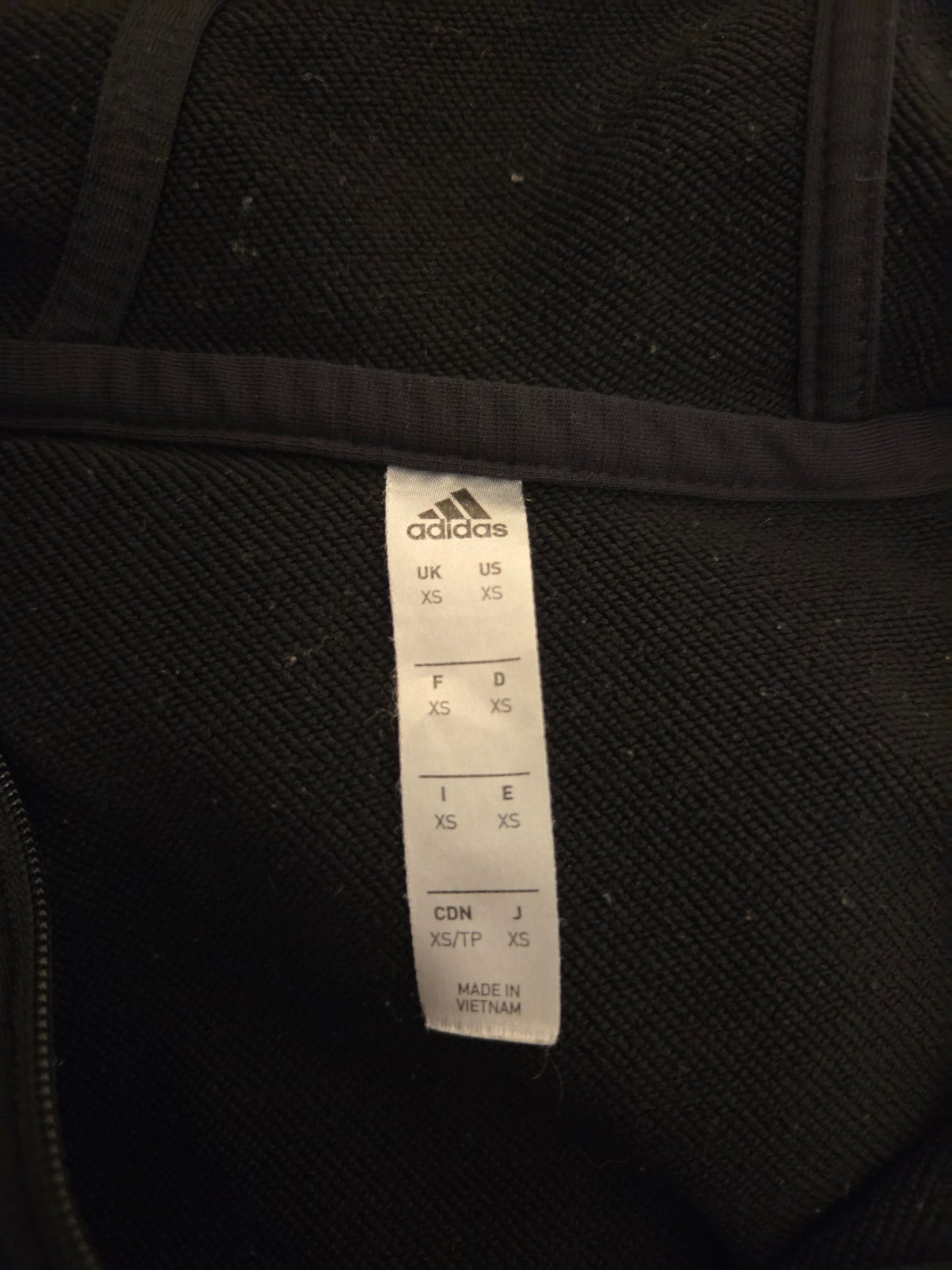 Black Adidas garment with a label on a black background