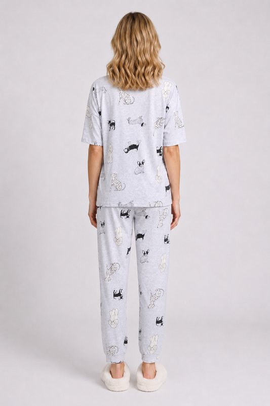 Woman wearing a light grey pajama set with black dog prints on
