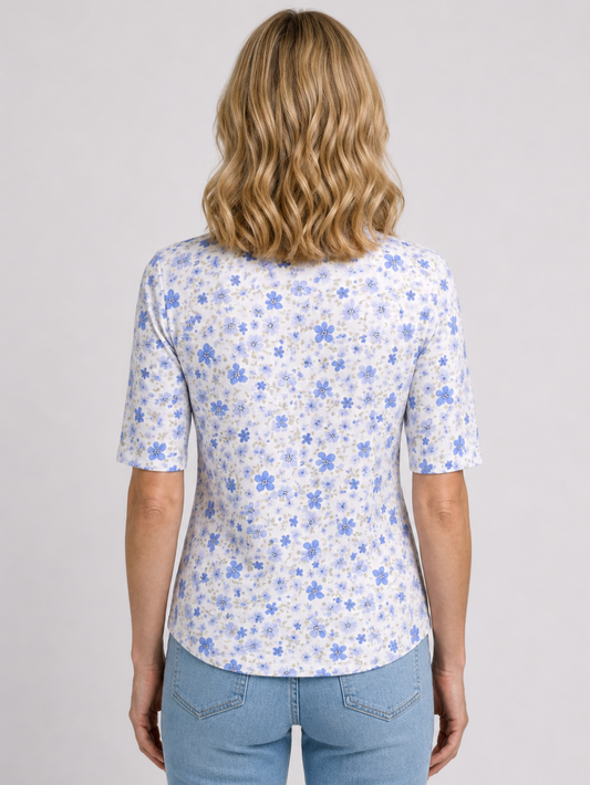 Woman wearing a white top with blue floral pattern and blue jeans