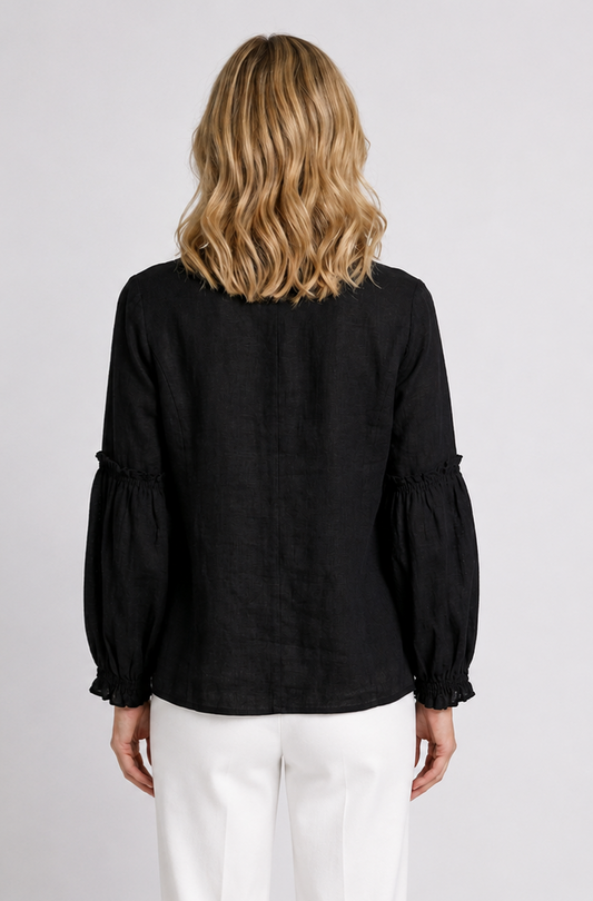 Person wearing a black tunic top with puffed sleeves
