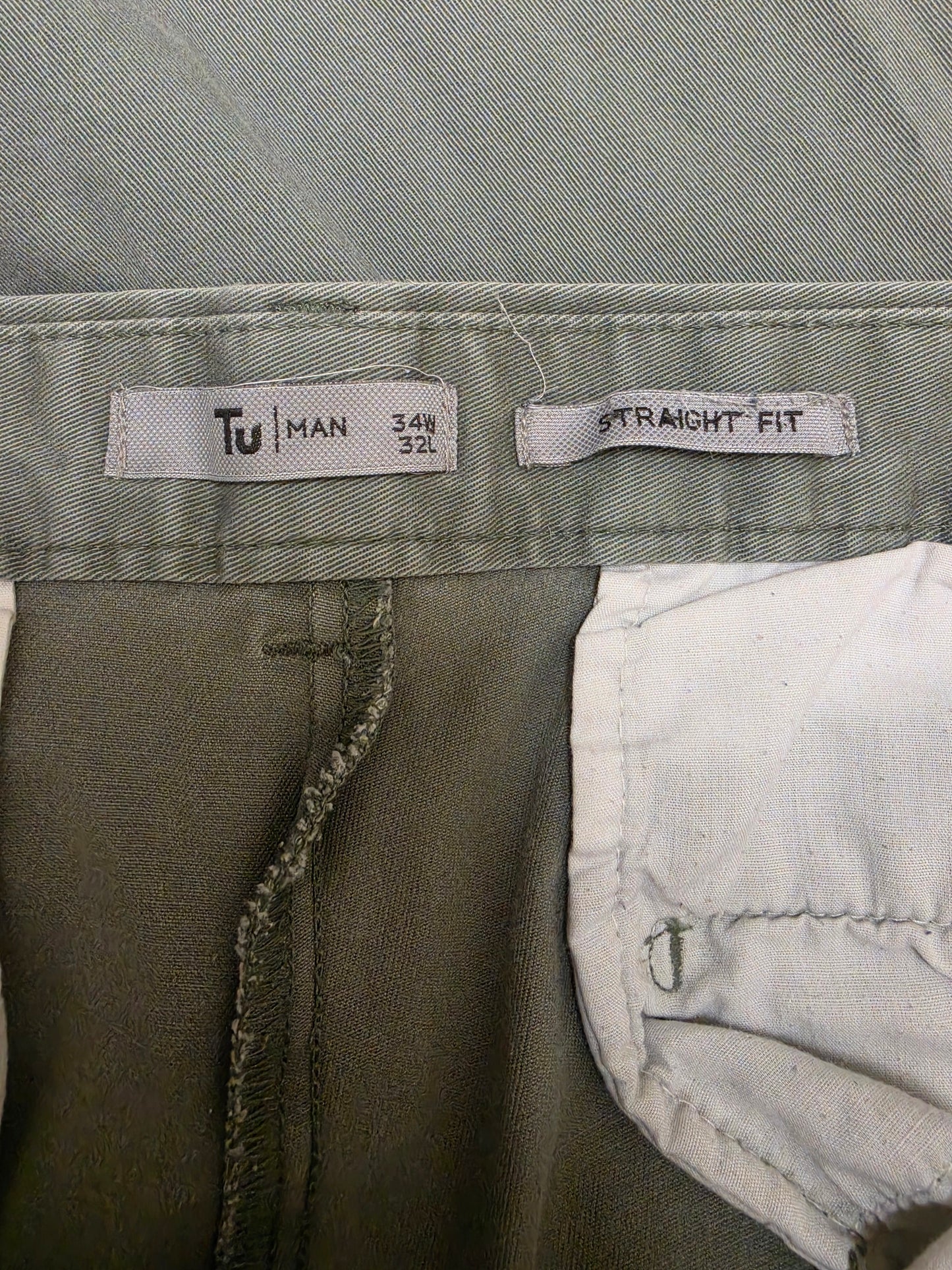 Close-up of the waistband of a pair of men's trousers, showing the size and fit labels.
