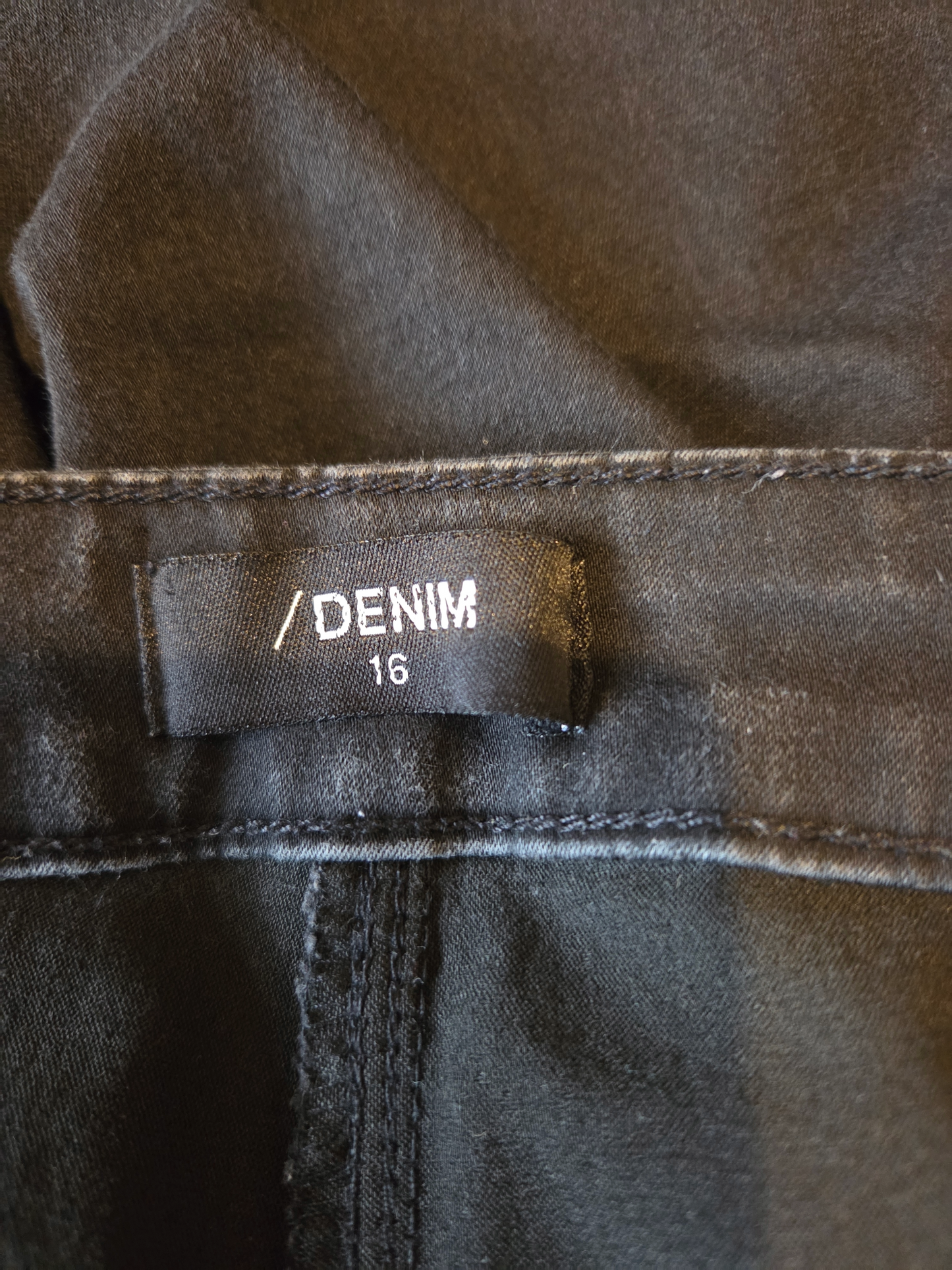 size label showing denim 16 on black fabric