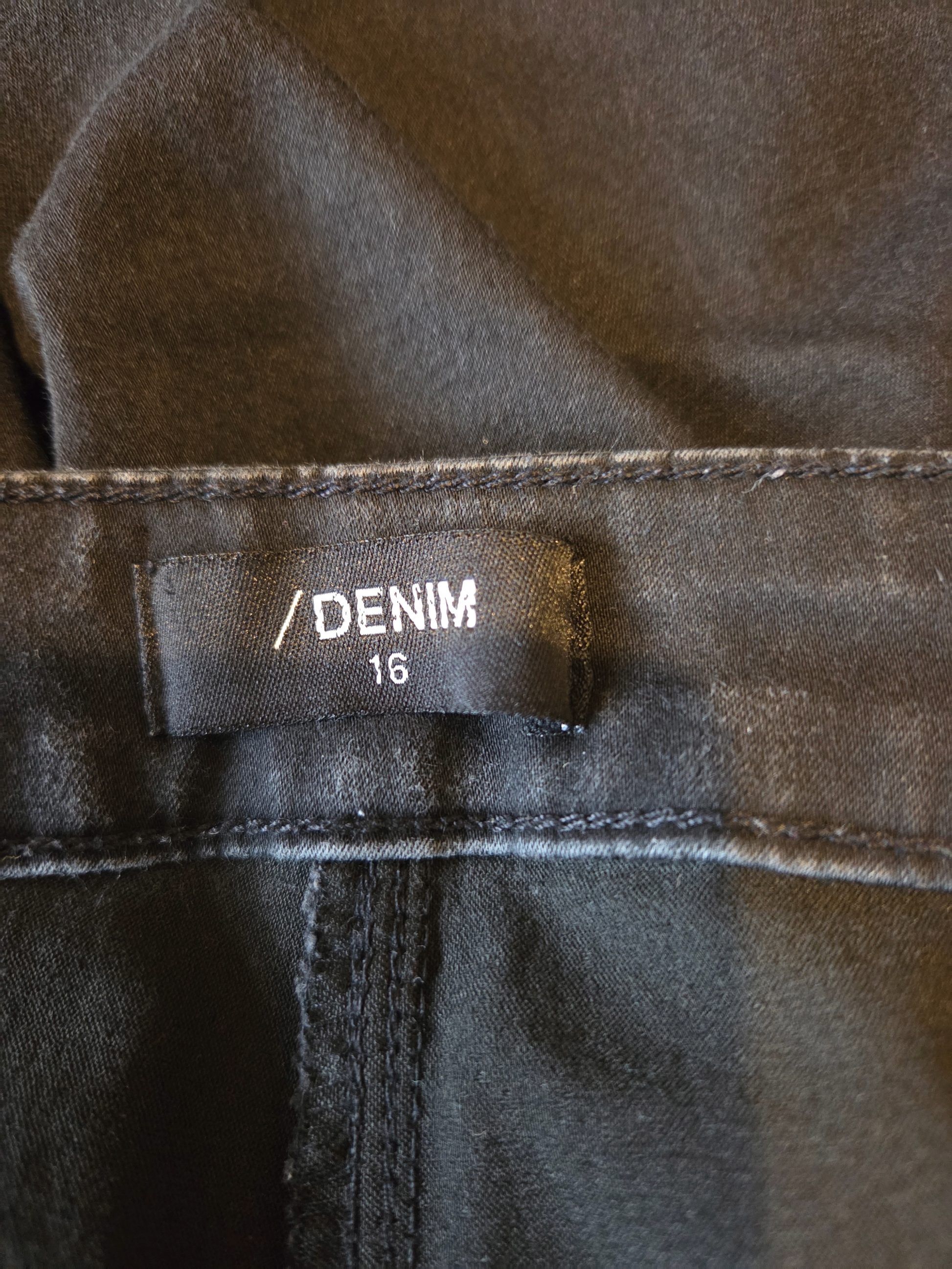 size label showing denim 16 on black fabric