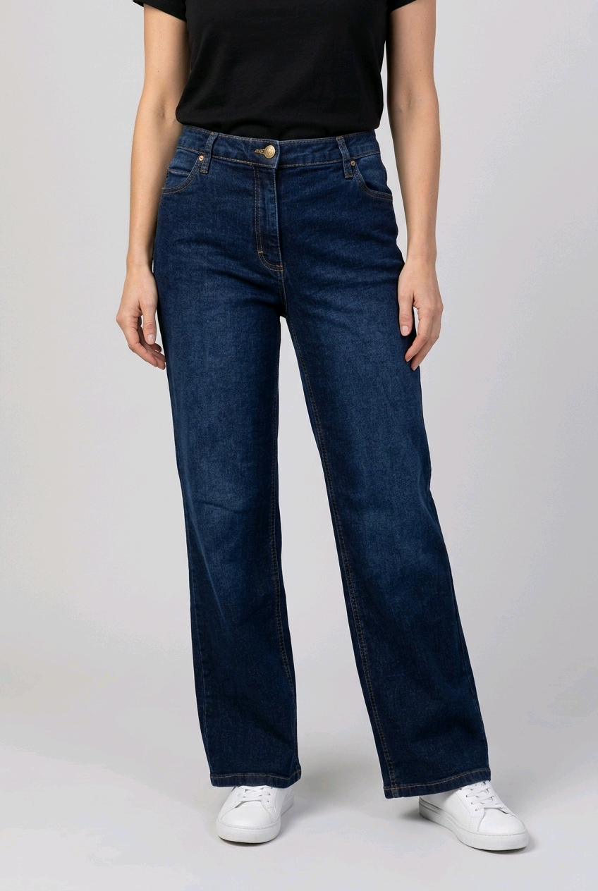 woman wearing dark blue jeans and a black top on a light gray background