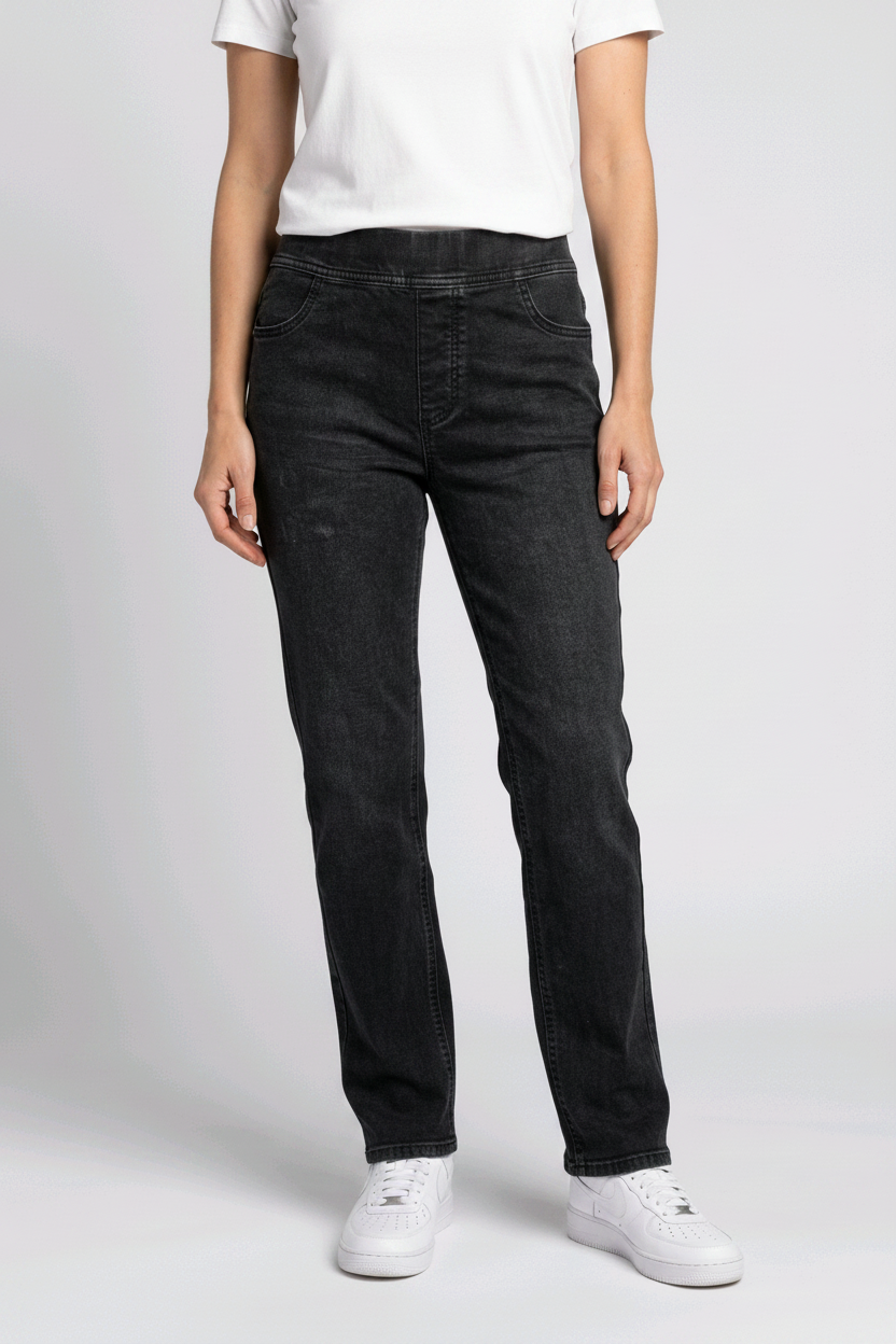 woman wearing black jeans and white trainers on a plain background