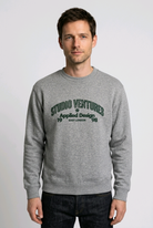 Man wearing a gray sweatshirt with 'Studio Ventures' text 
