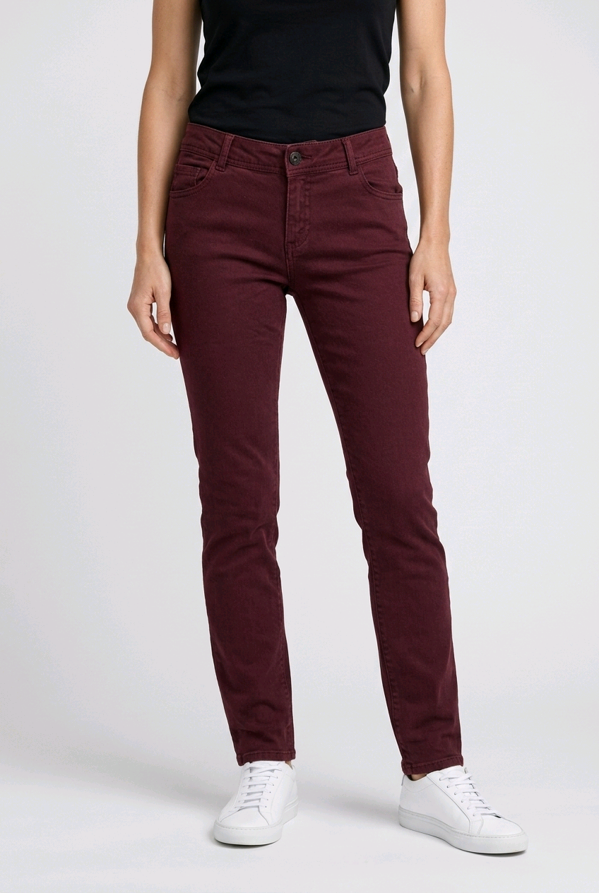 woman wearing maroon pants and white trainers on a white background