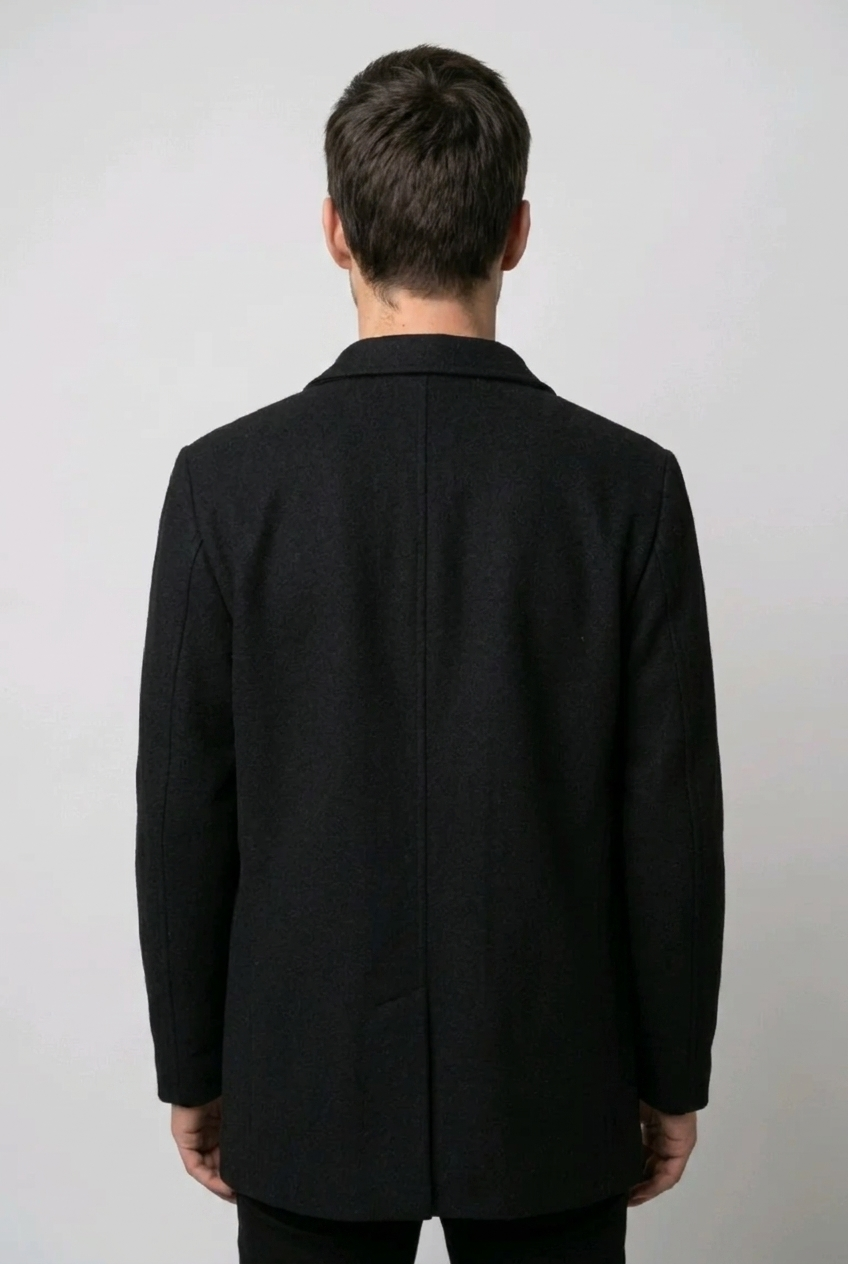 Person wearing a black coat from behind on a plain background