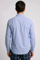Man wearing a light blue button-up pyjama shirt and plaid pants 