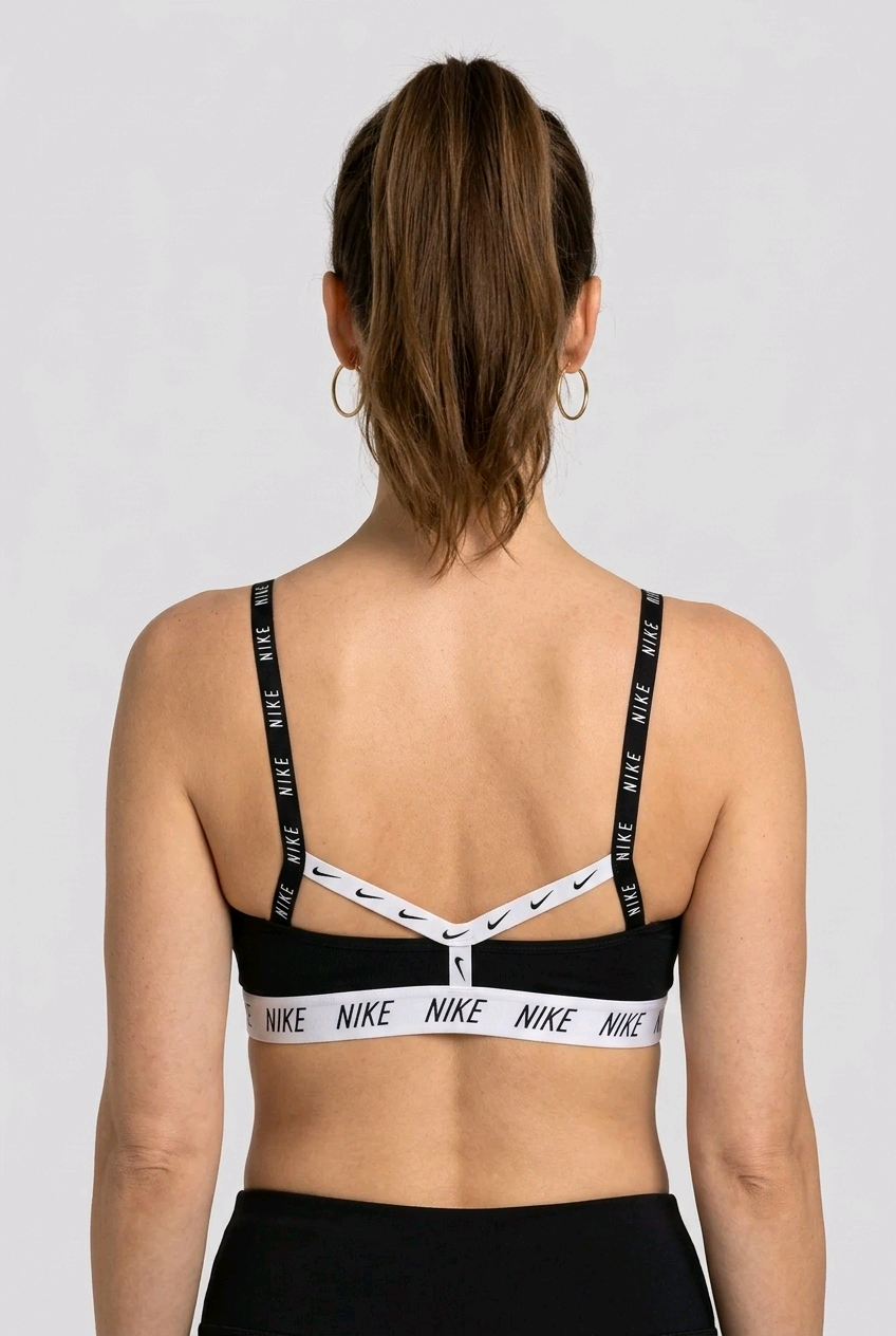Womenswearing a black Nike sports bra with white logo straps back view