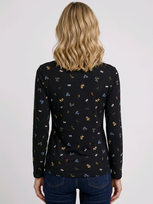 Person wearing a black long-sleeve top with small colourful patterns 