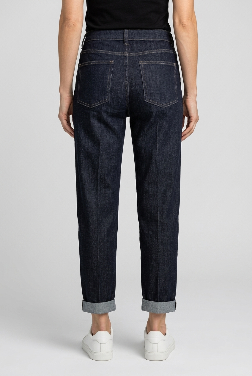 woman wearing dark blue jeans on a plain background