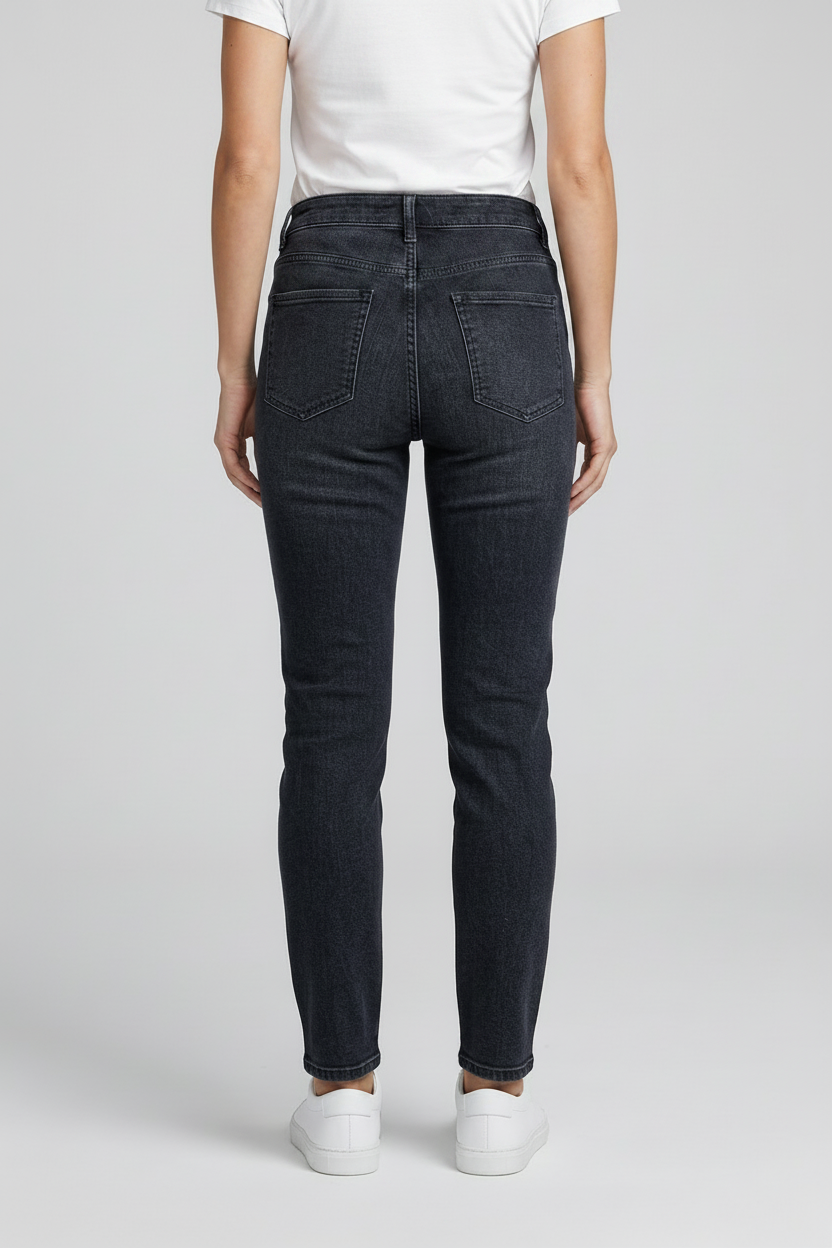 Person wearing dark blue jeans and a black top on a light gray background