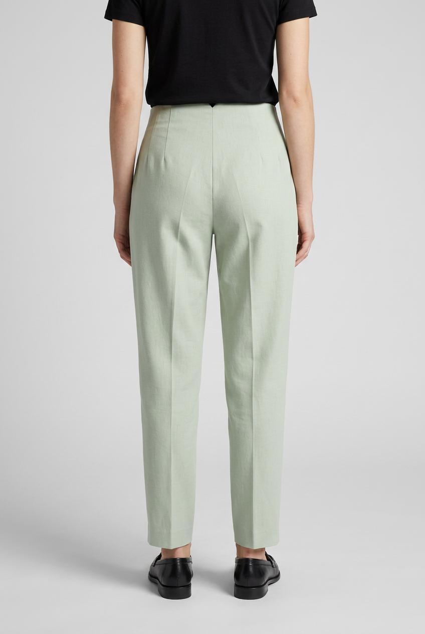 Woman wearing light green trousers and black shoes 