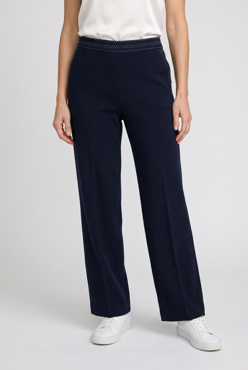 Woman wearing navy trousers and a white t shirt