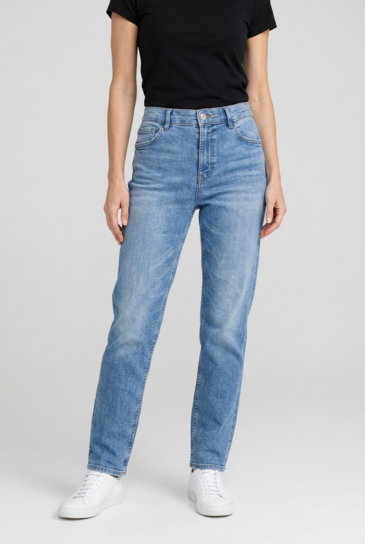Person wearing light blue jeans and a black top on a plain background