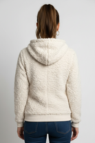 Woman wearing a cream sherpa jacket on a plain background