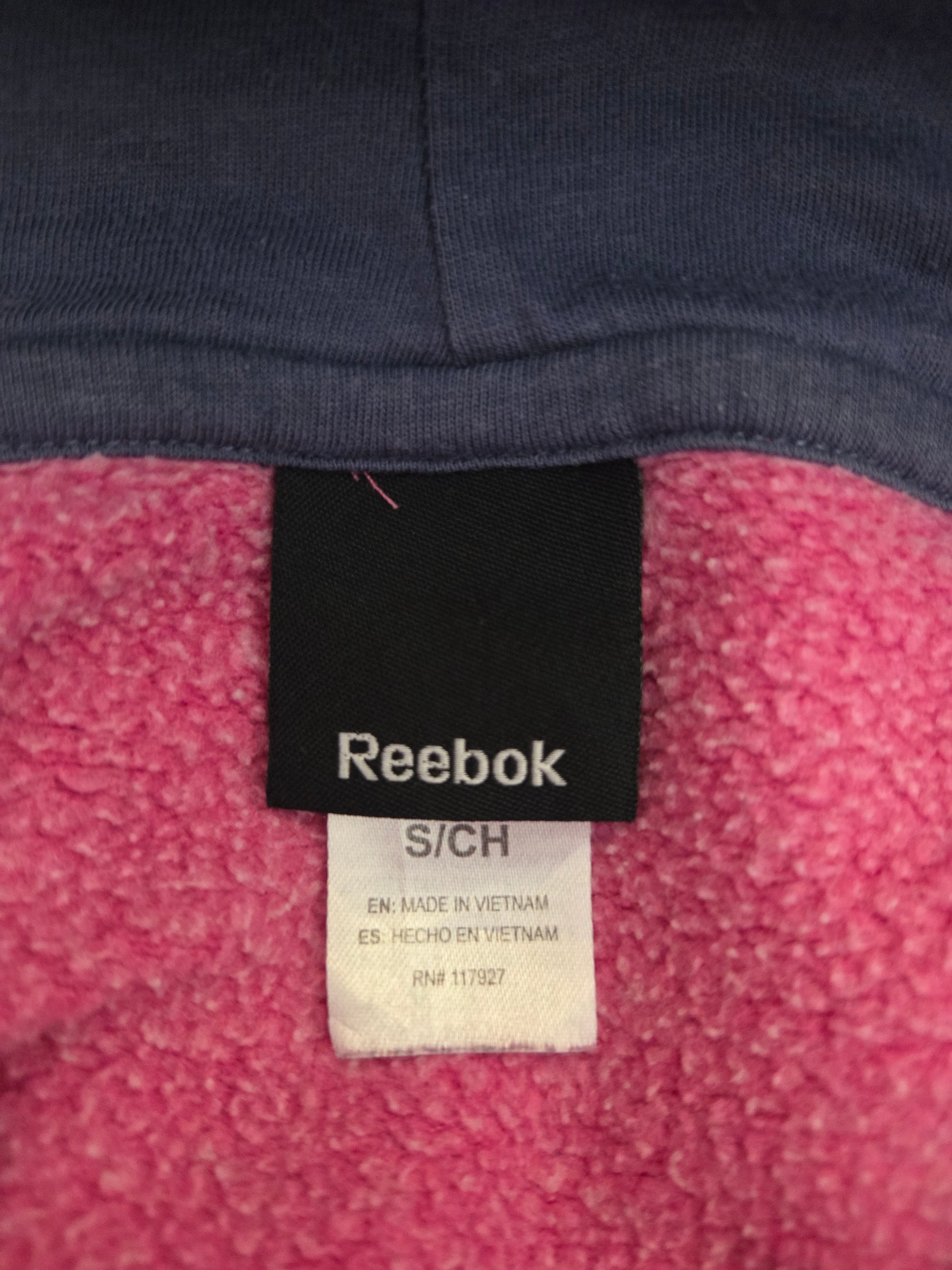 Close-up of Reebok size label on a pink and navy fabric background