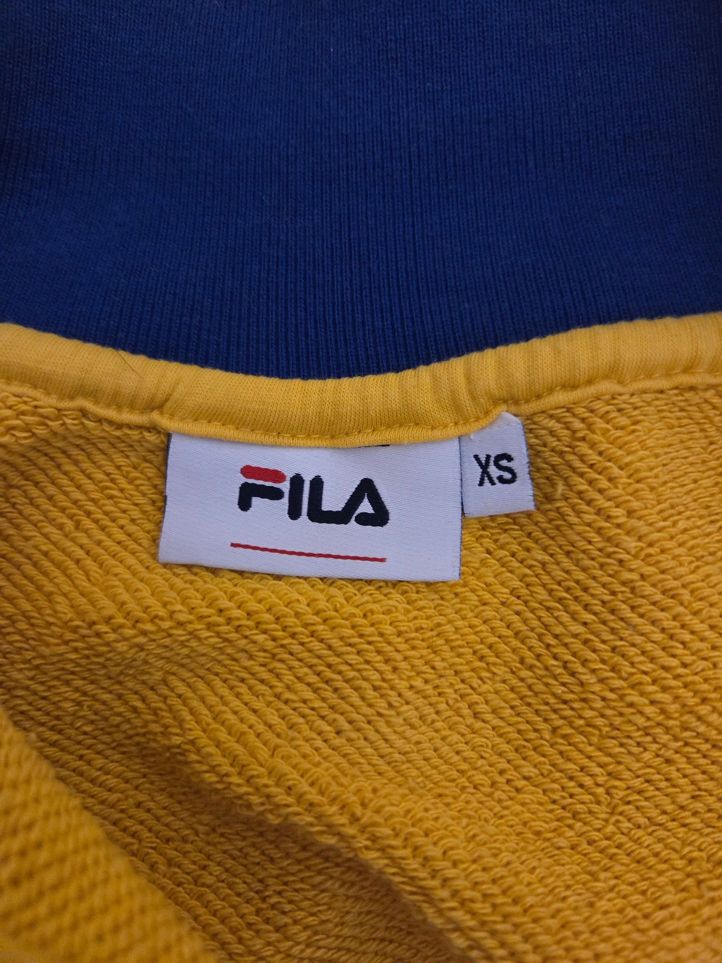 Close-up of a yellow fabric with a FILA label on a blue background