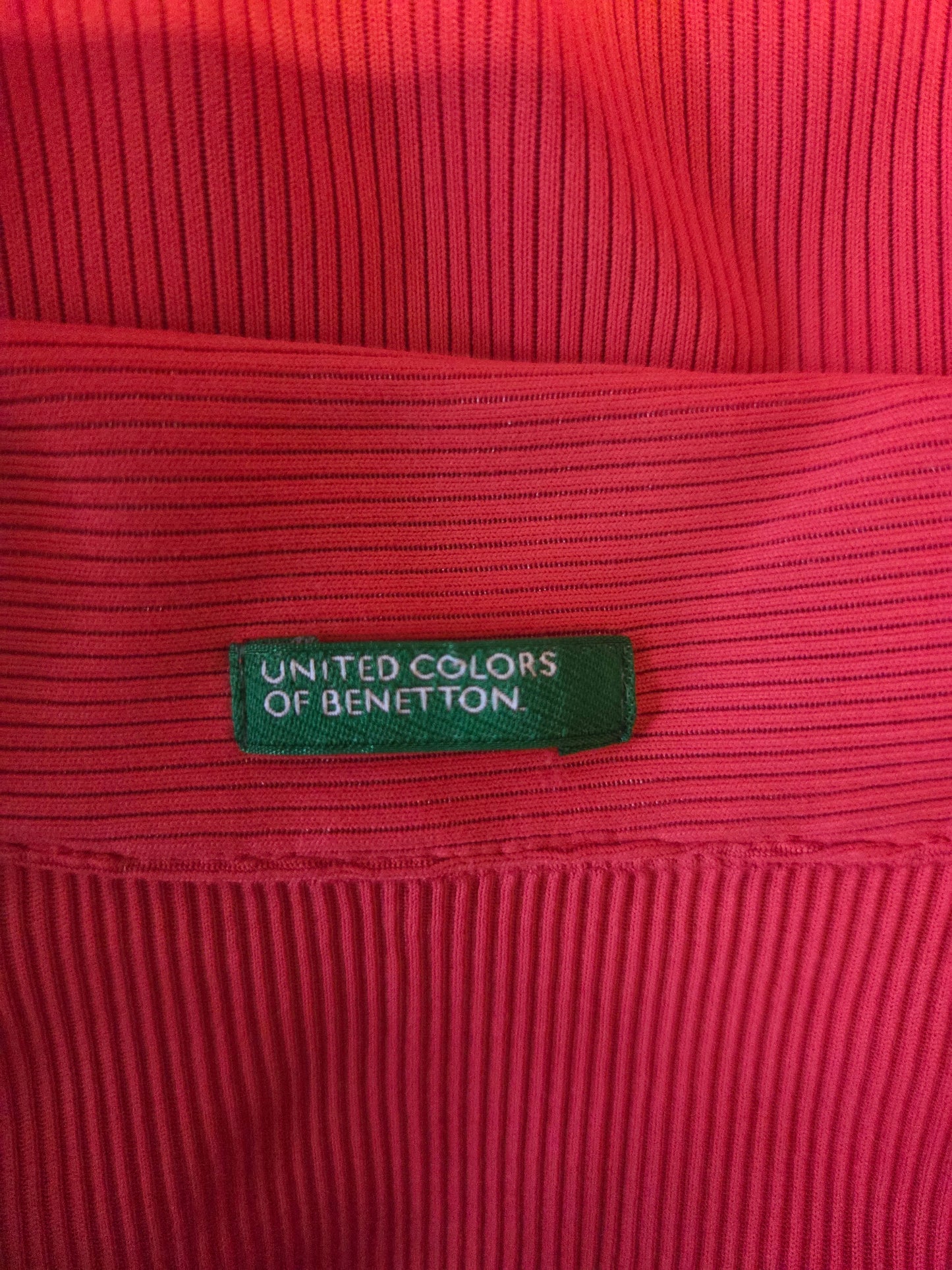 Red ribbed fabric with a green label reading 'United Colors of Benetton'.