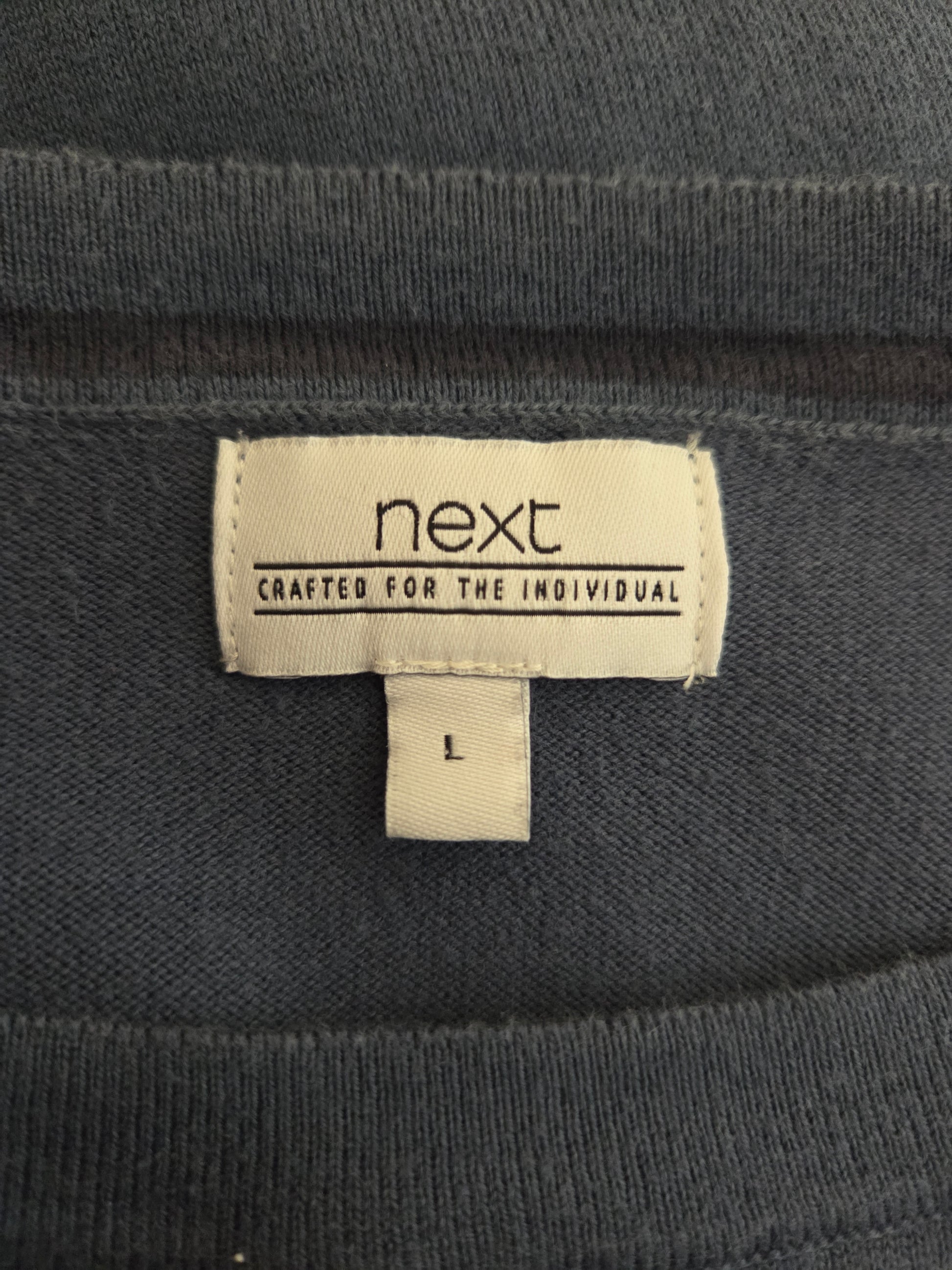 Close-up of a 'next' label on a dark fabric background