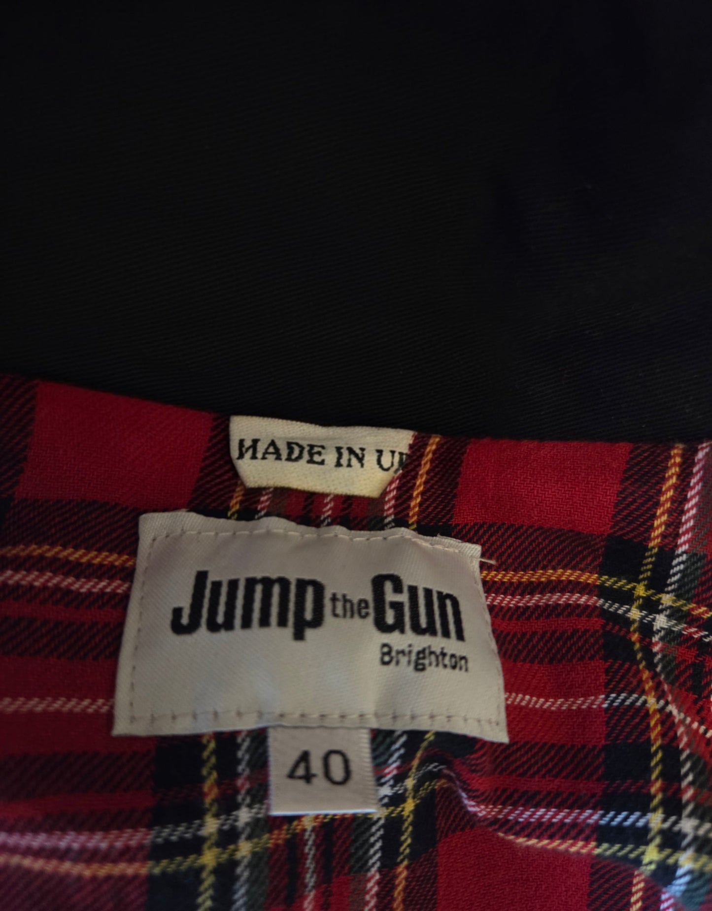 Plaid fabric with 'Jump the Gun' label and size 40 on a dark background