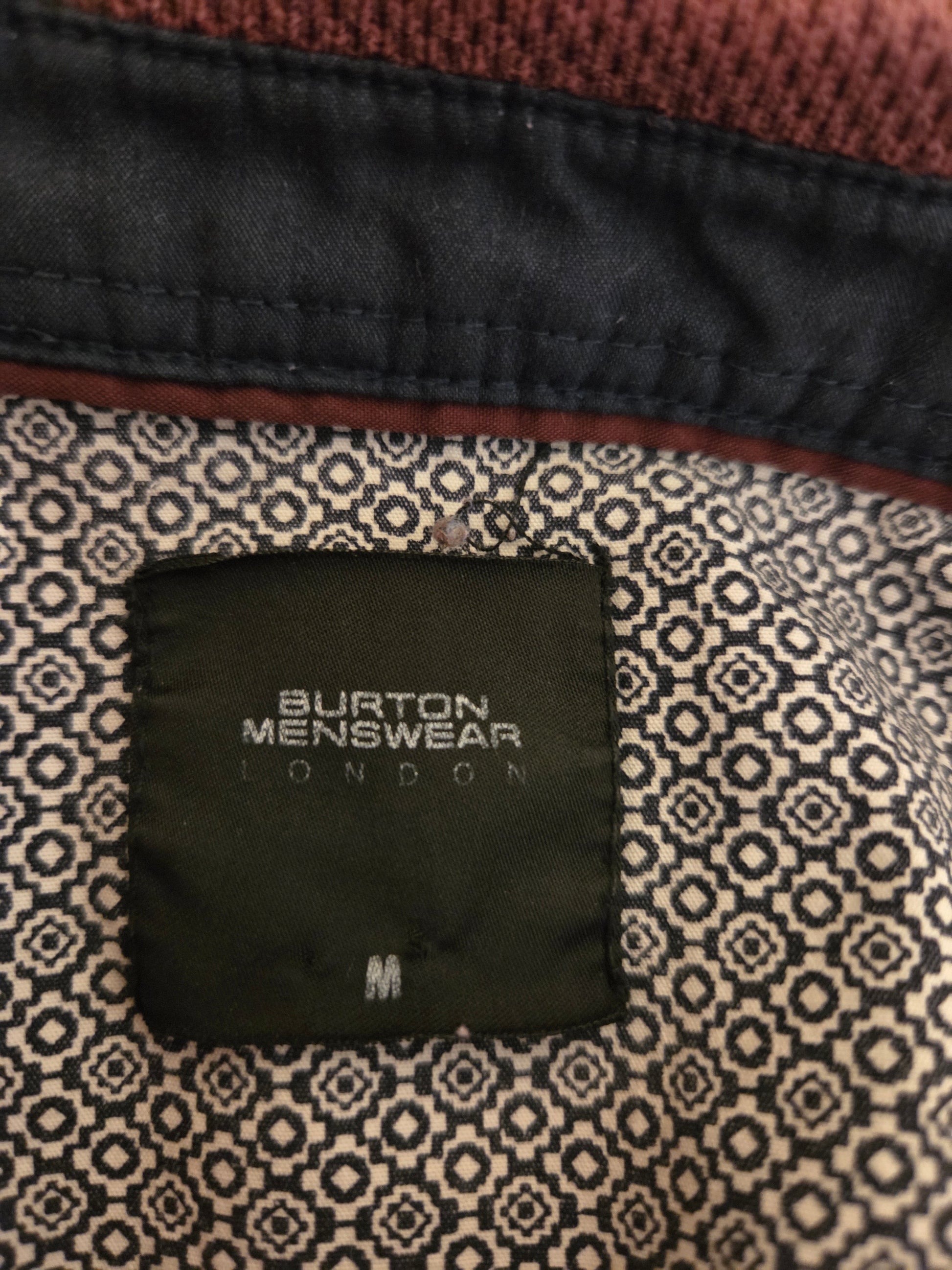 Close-up of a Burton Menswear London label on patterned fabric.