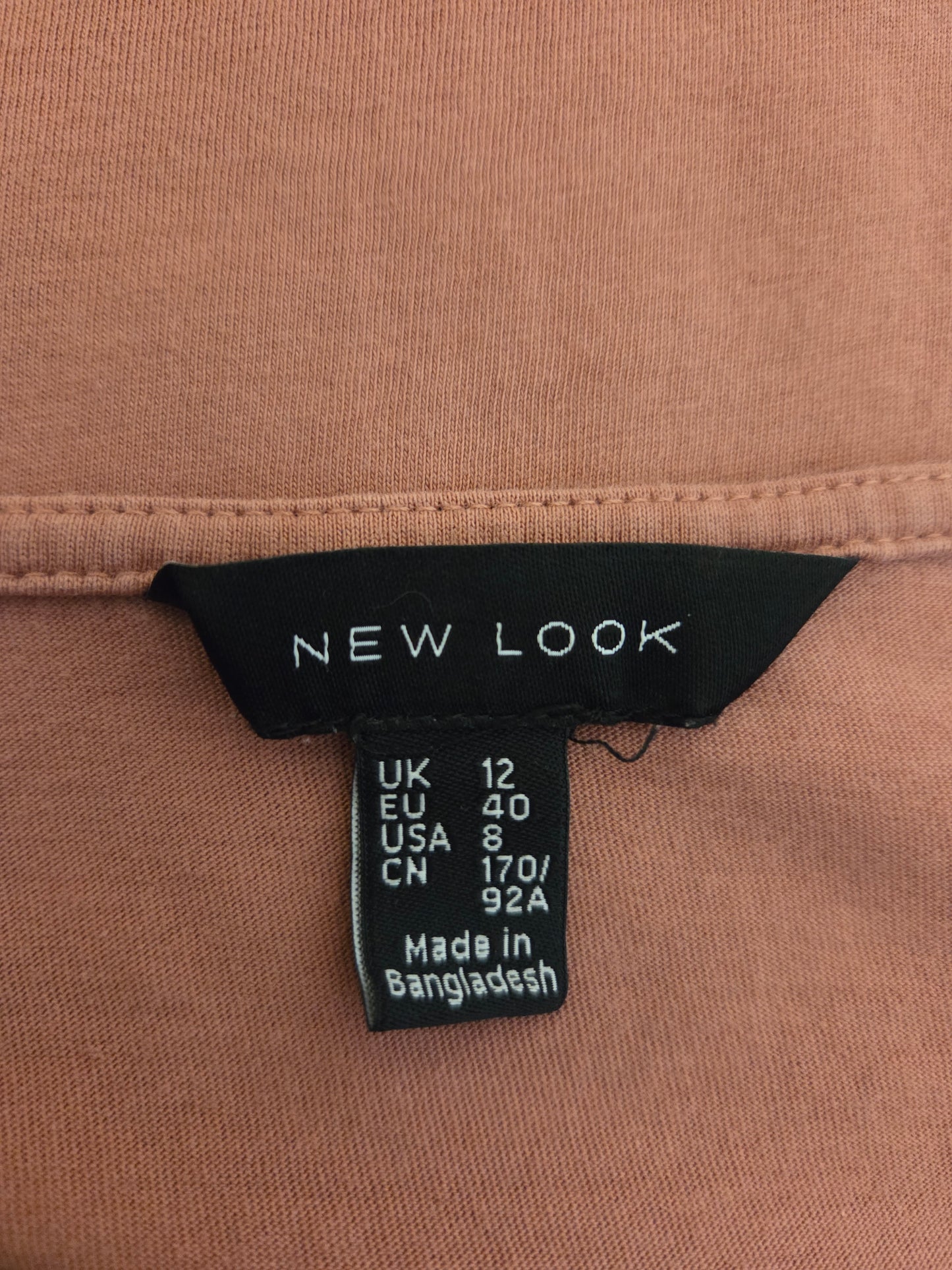 Close-up of a 'New Look' label on a dusty rose fabric background