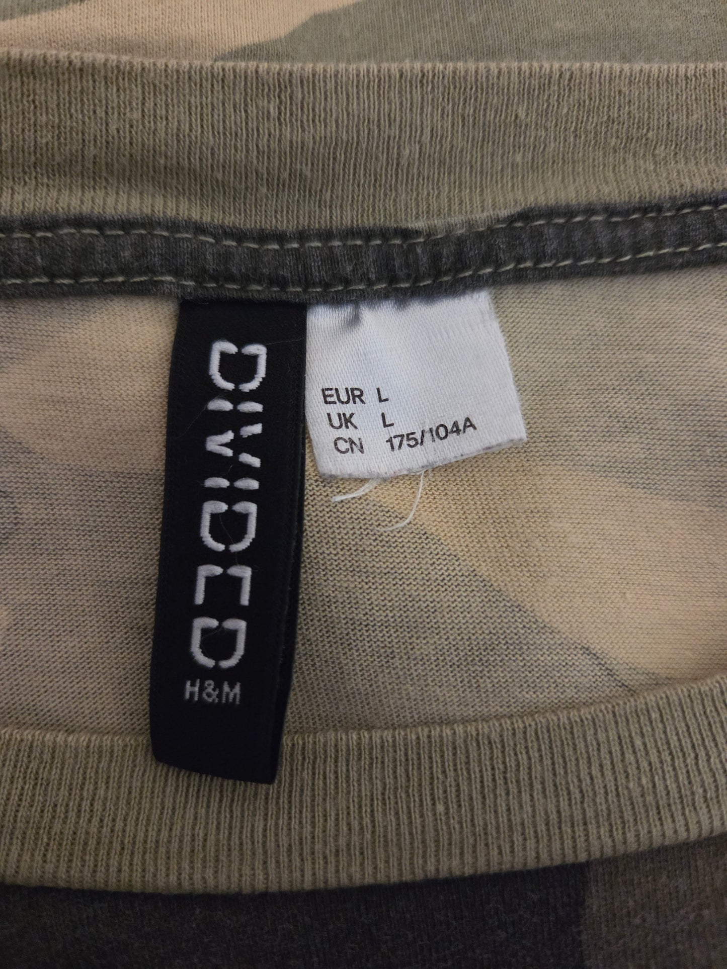 Close-up of a 'Divided H&M' label on a garment with camouflage pattern.