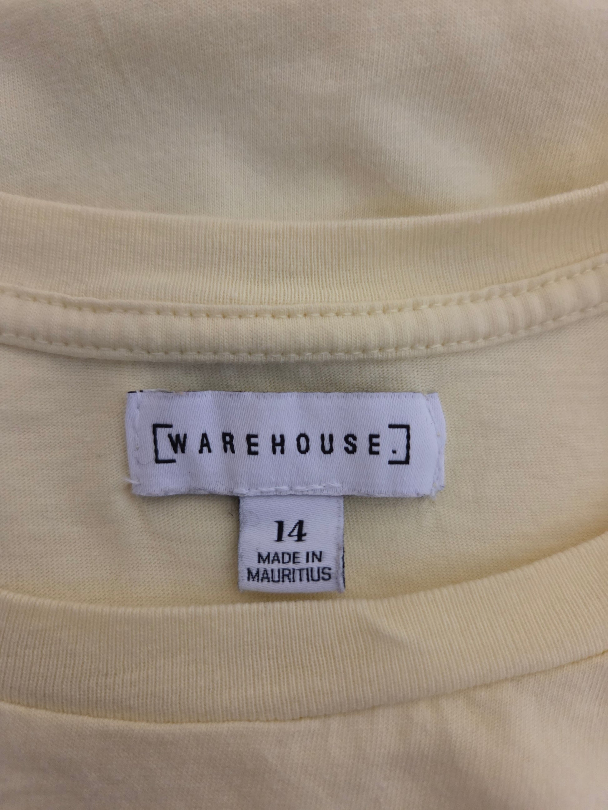 Close-up of a yellow fabric with a 'Warehouse'  size label 