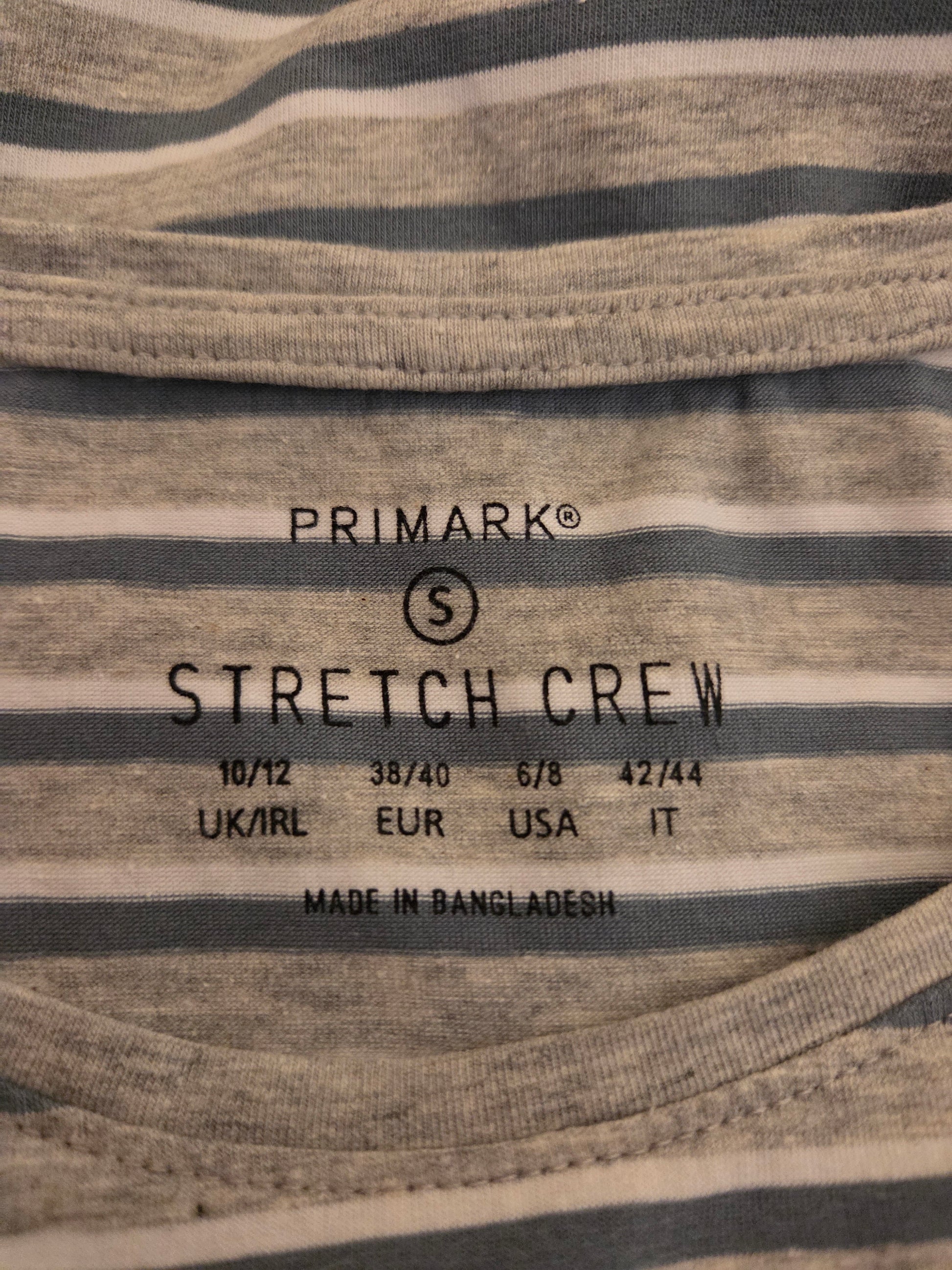 Close-up of a Primark stretch crew label on striped fabric.