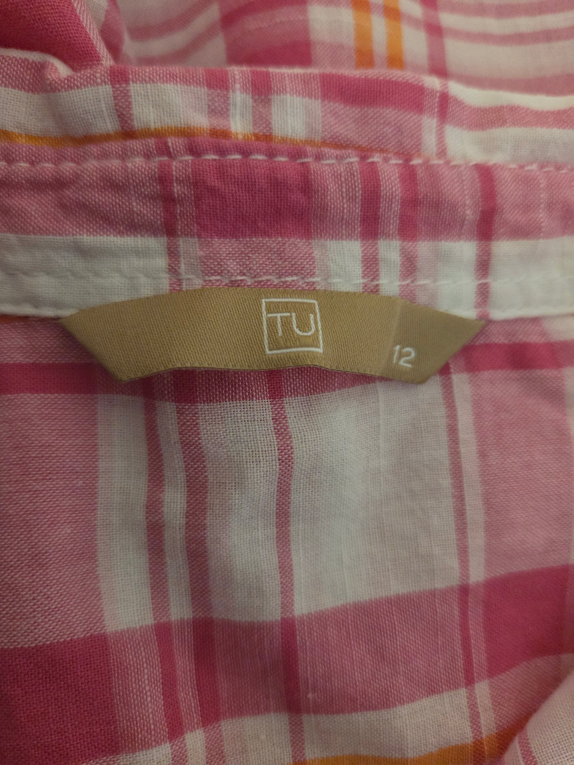 Close-up of a size label on a pink and white checkered background.